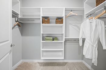 A white closet with a white robe hanging on the right side.